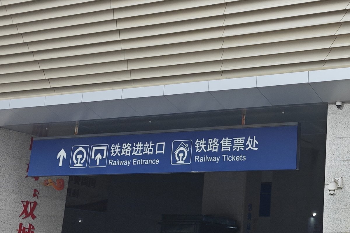 Bilingual overhead sign at a Chinese railway station reading Railway Entrance and Railway Tickets.