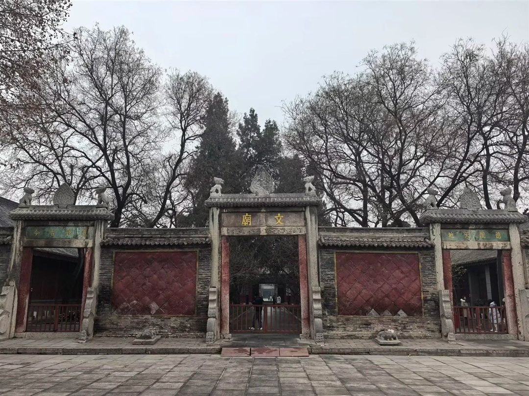 The Confucian temple gate wall, a central gate with a gold 文廟 plaque flanked by two side gates whose green-and-gold plaques read 道冠古今 and 德配天地.
