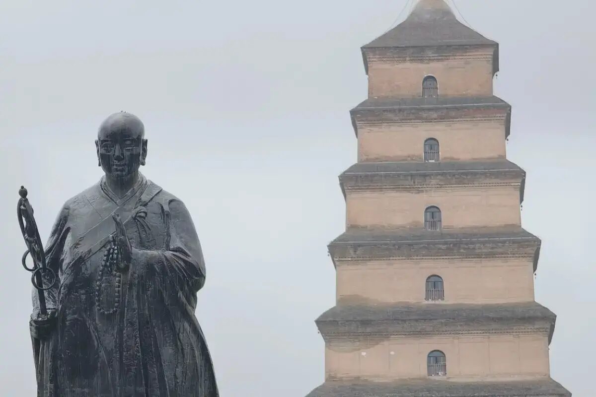 Bronze statue of the monk Xuanzang in front of the square brick Big Wild Goose Pagoda, Xi'an.
