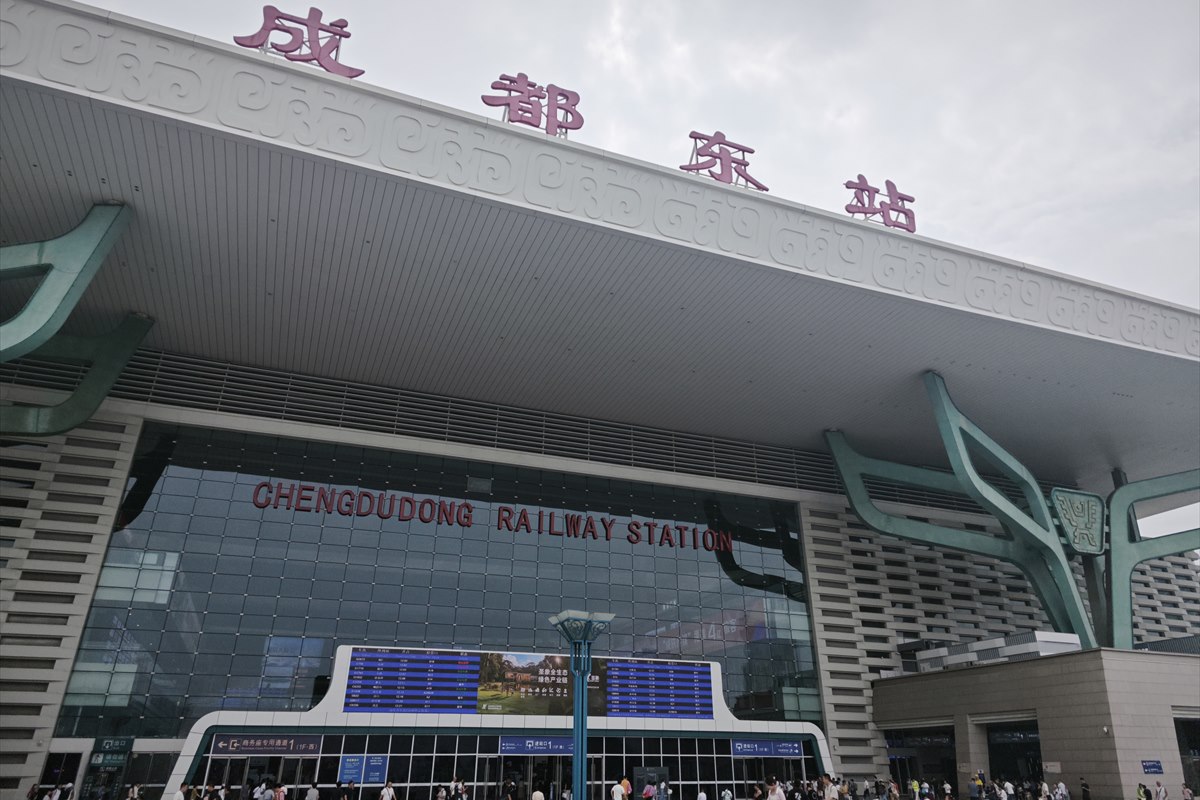 The main frontage of Chengdu East Railway Station, its name in Chinese above a bronze-motif frieze and in English on the glass below.