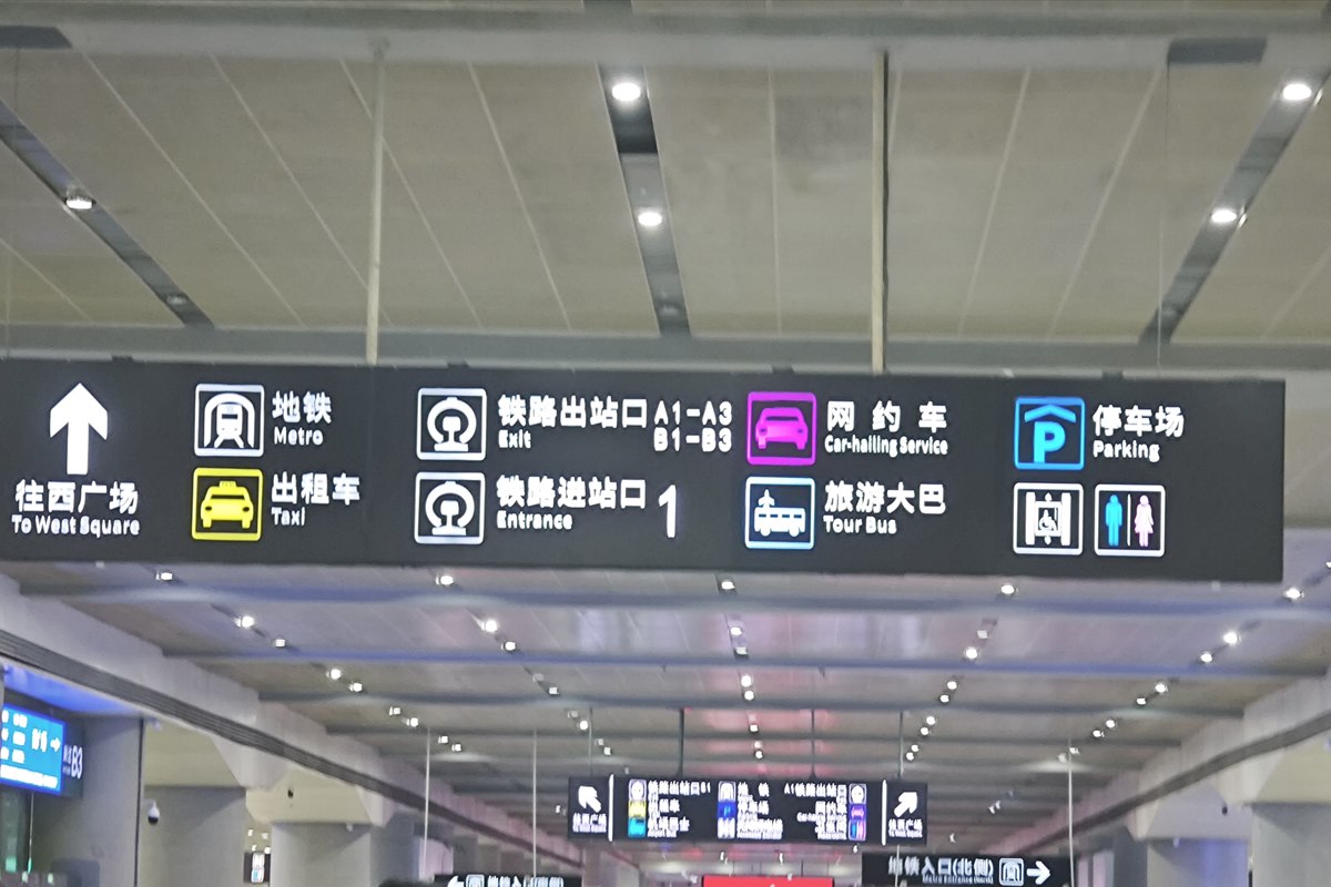 A bilingual overhead sign in the Chengdu East arrivals concourse listing Metro, Taxi, Exit, Entrance, Car-hailing Service, Tour Bus and Parking.