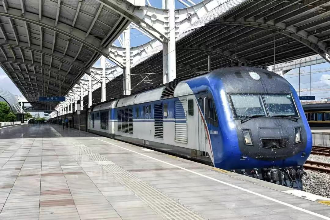 Blue and grey conventional locomotive-hauled Z-series train waiting at a covered station platform