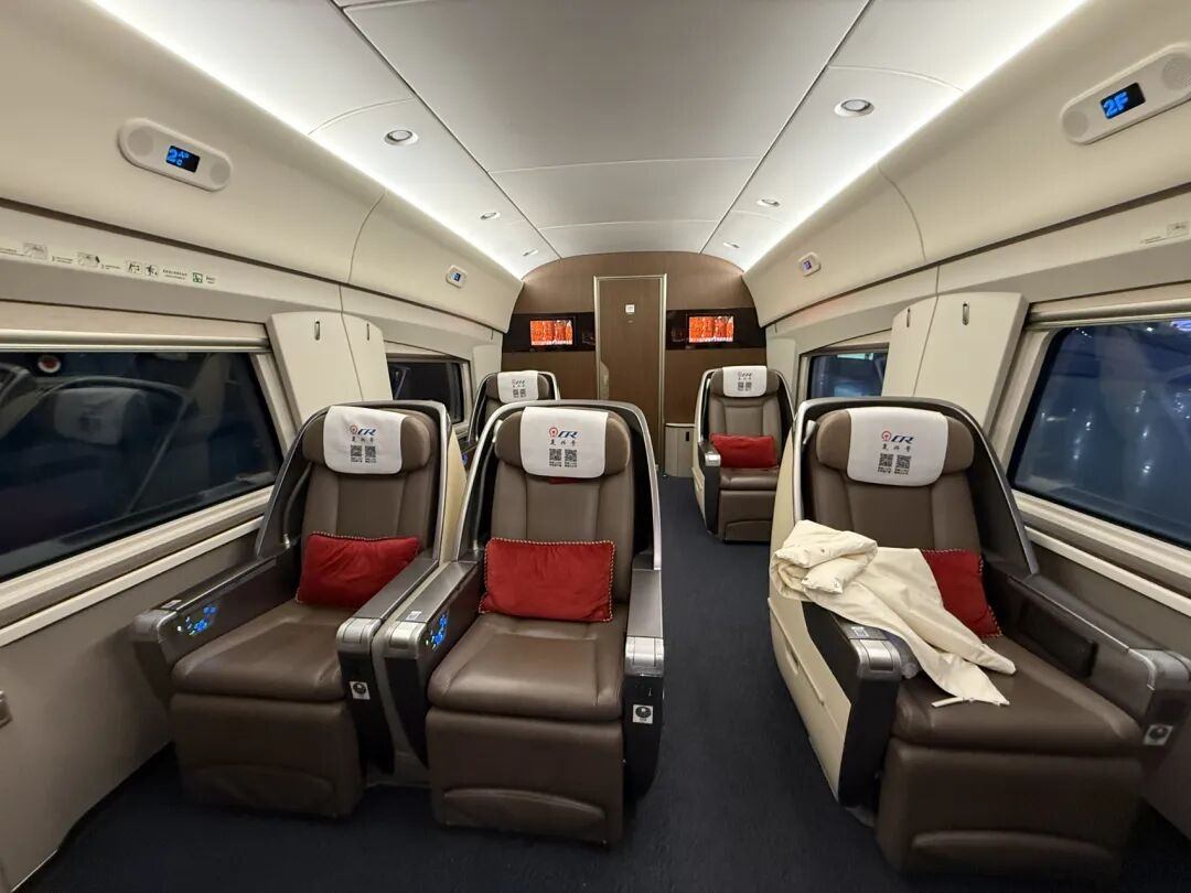 Business-class cabin of a China high-speed train with 2 plus 1 brown leather flat-recline seats and red cushions
