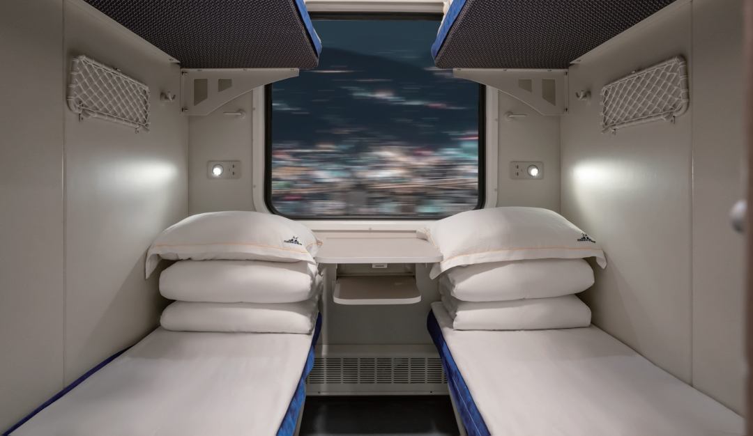 Soft-sleeper compartment on a conventional Chinese train: four berths, a window table, and a door that closes
