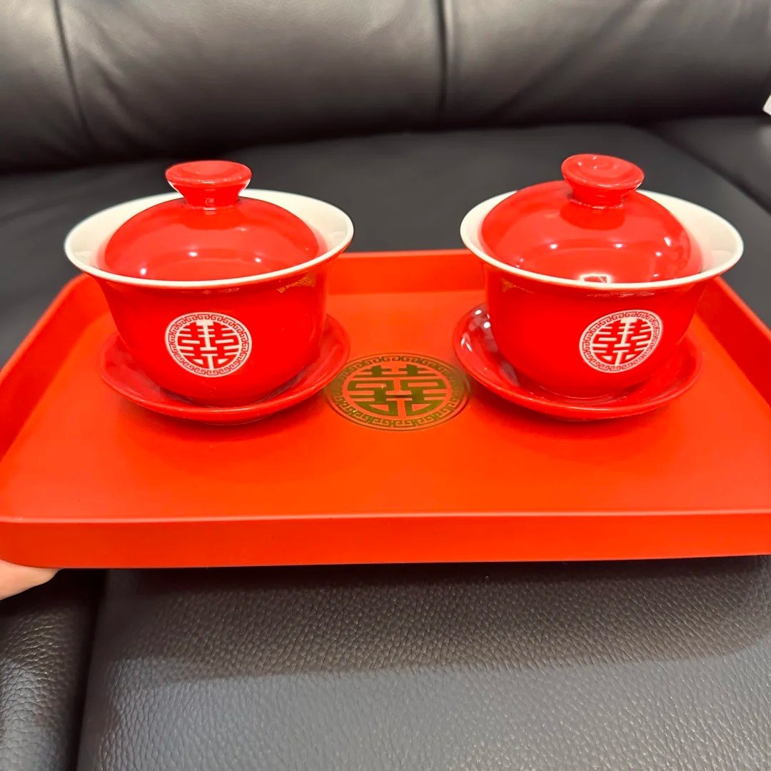 A pair of red lidded tea bowls marked with the double-happiness character on a red lacquer tray