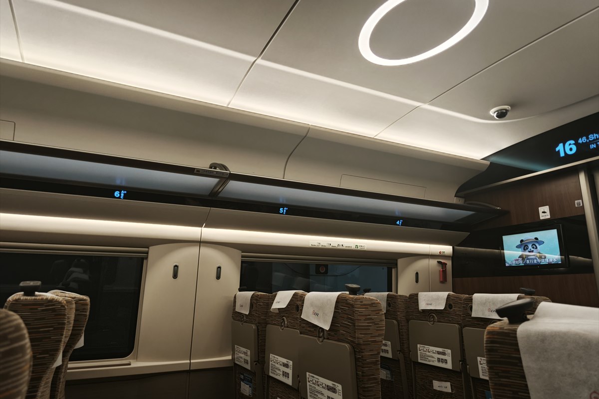 The interior of a second-class carriage on a Fuxing high-speed train, with 3+2 seating, overhead racks and a carriage-number display.