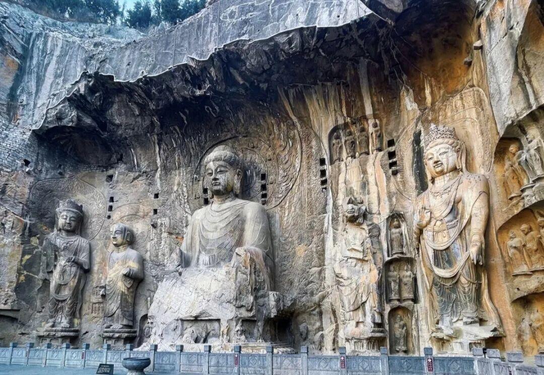 The Fengxian Temple group at the Longmen Grottoes near Luoyang — the large seated Vairocana Buddha carved into the cliff, flanked by attendant figures.
