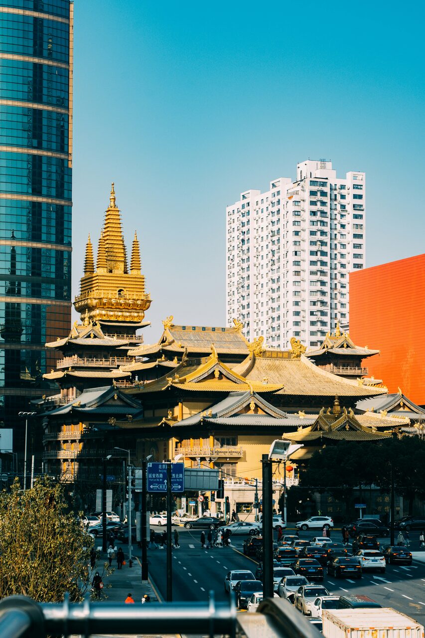 Jing'an Temple's gold-leafed roofs and pagoda in central Shanghai, ringed by a white residential tower and office buildings.