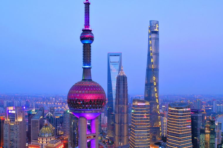 Shanghai Oriental Pearl Tower lit up at night across the Huangpu River — landmark of the Pudong skyline.