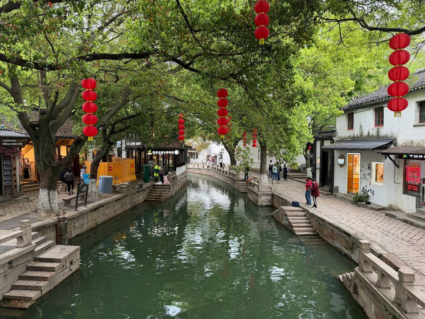 A stone-lined canal on Pingjiang Road in Suzhou's old town, hung with red lanterns and lined with white-walled Ming-era houses.