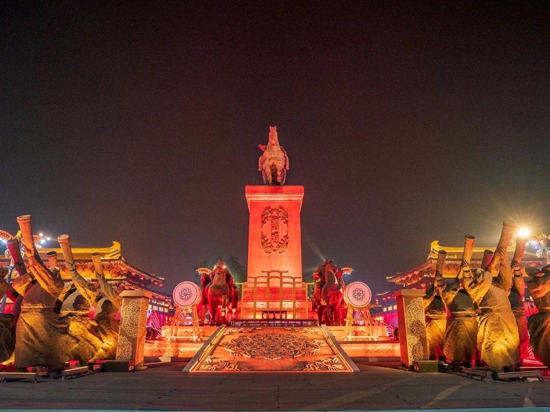 The Taizong monument seen head-on up its ceremonial axis, with a carved medallion floor panel, symmetric ranks of bronze horn-bearers, two flanking horses and two painted drums.