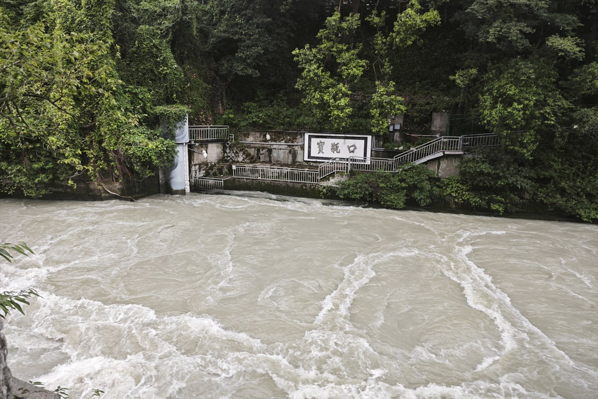 The Baopingkou bottle-neck channel at Dujiangyan, water surging past an inscribed stone plaque on the far bank.