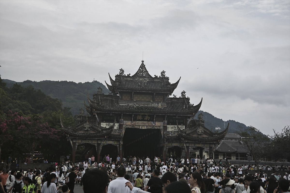 The multi-tiered covered gatehouse of Nanqiao Bridge in Dujiangyan town, crowded with visitors.