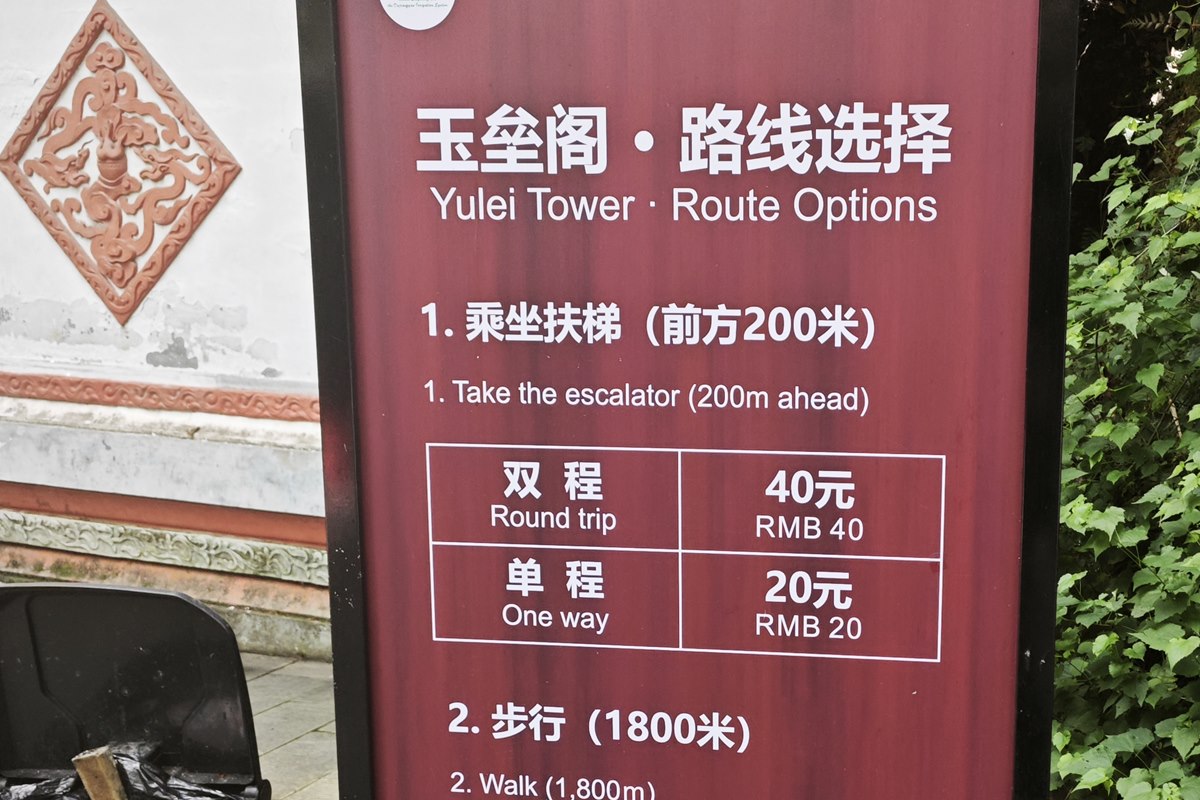 Bilingual scenic-area board headed Yulei Tower Route Options, listing the escalator round-trip and one-way fares and the walking alternative.