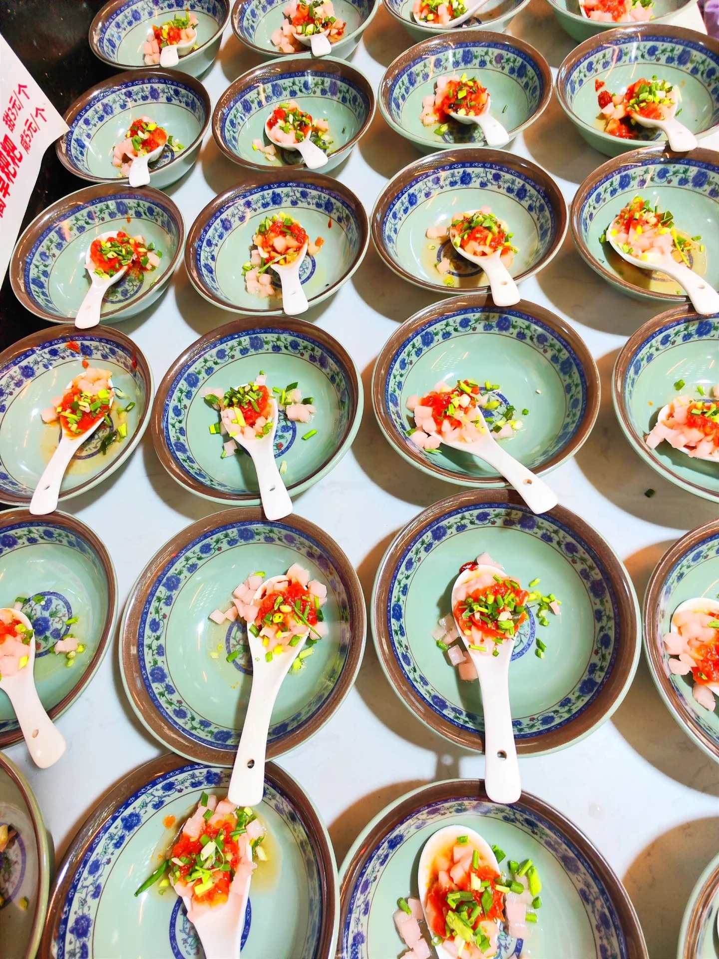 Bowls of Furong rice tofu (米豆腐) — soft rice jelly topped with a sour-and-spicy sauce, pickle and spring onion, the town's signature snack from the 1986 film.