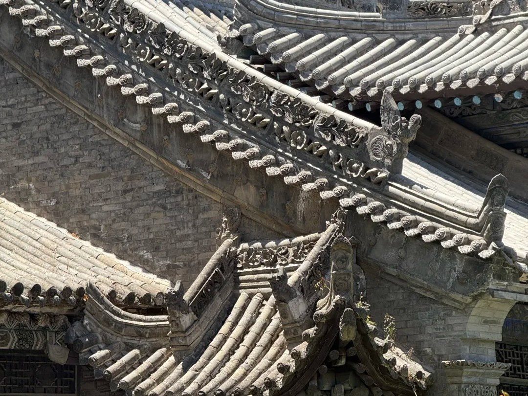 Three receding grey clay-tile roofs with carved floral ridge courses and a chiwen ridge ornament, above grey brick gables — no dome and no minaret anywhere.