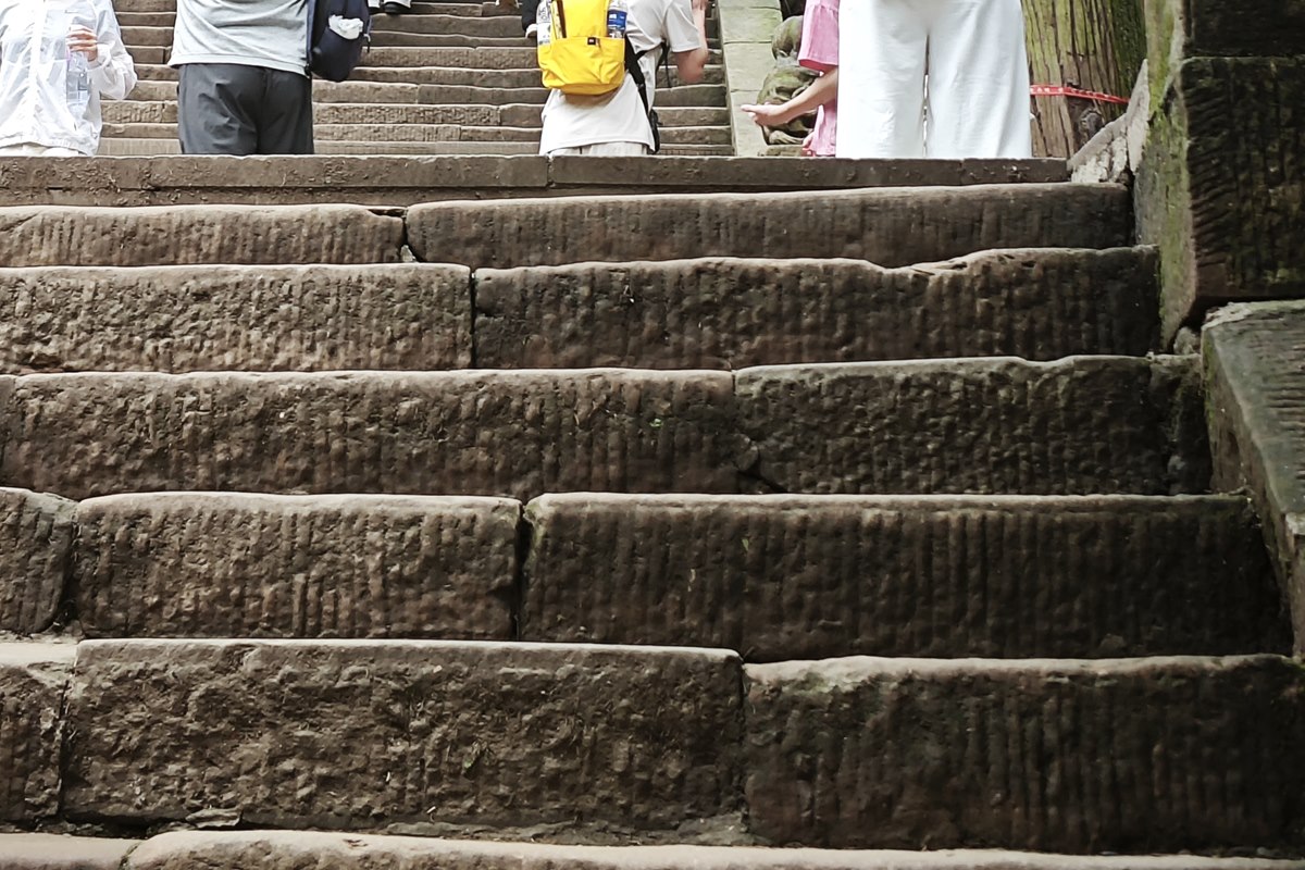 Worn stone treads on the descent path at Mount Qingcheng, dished hollow rather than flat.