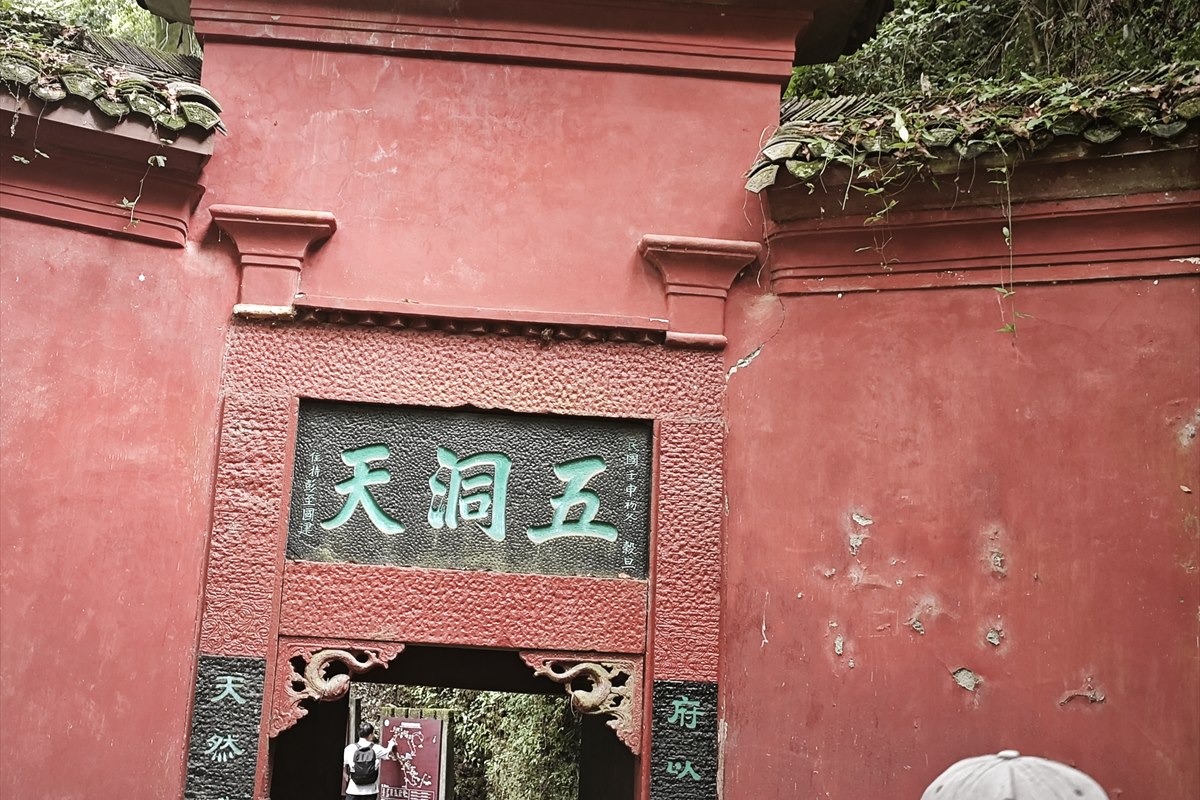 A red-walled gateway on Mount Qingcheng with a green-lettered plaque reading 五洞天.
