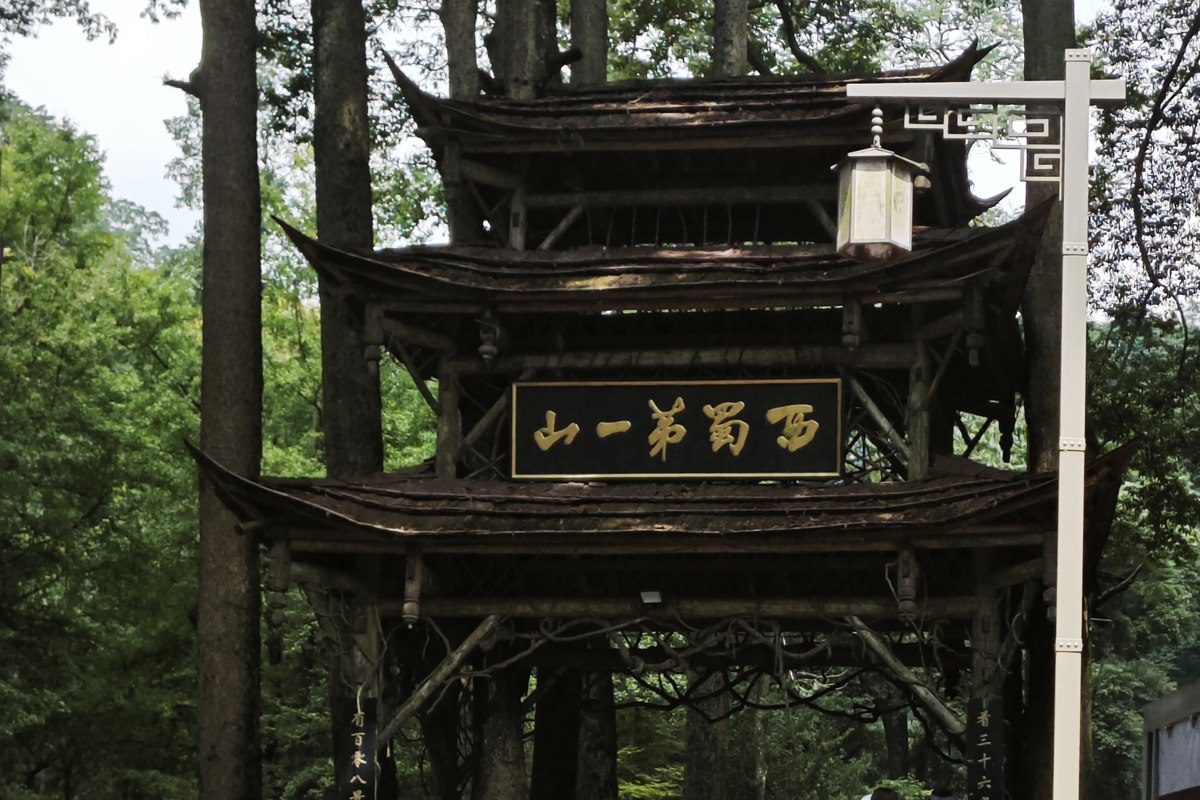 The three-tiered timber archway at Mount Qingcheng’s front gate, its gold plaque reading 西蜀第一山.