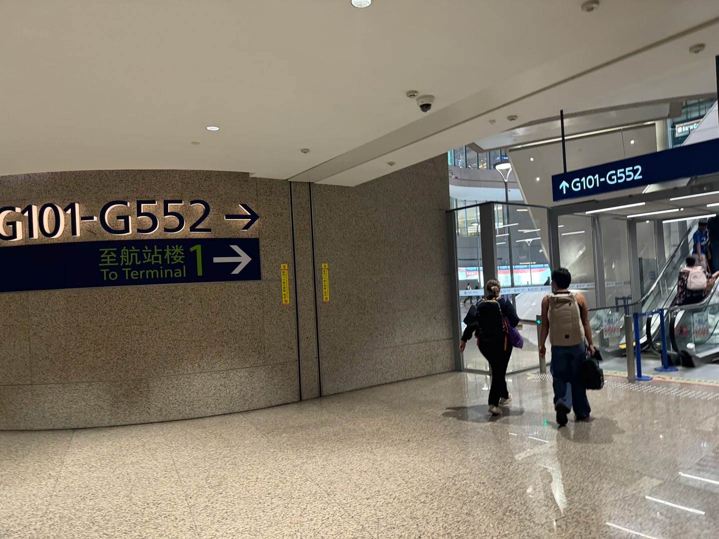 PVG wayfinding sign for gates G101-G552 pointing toward the satellite concourse, with a separate arrow to Terminal 1