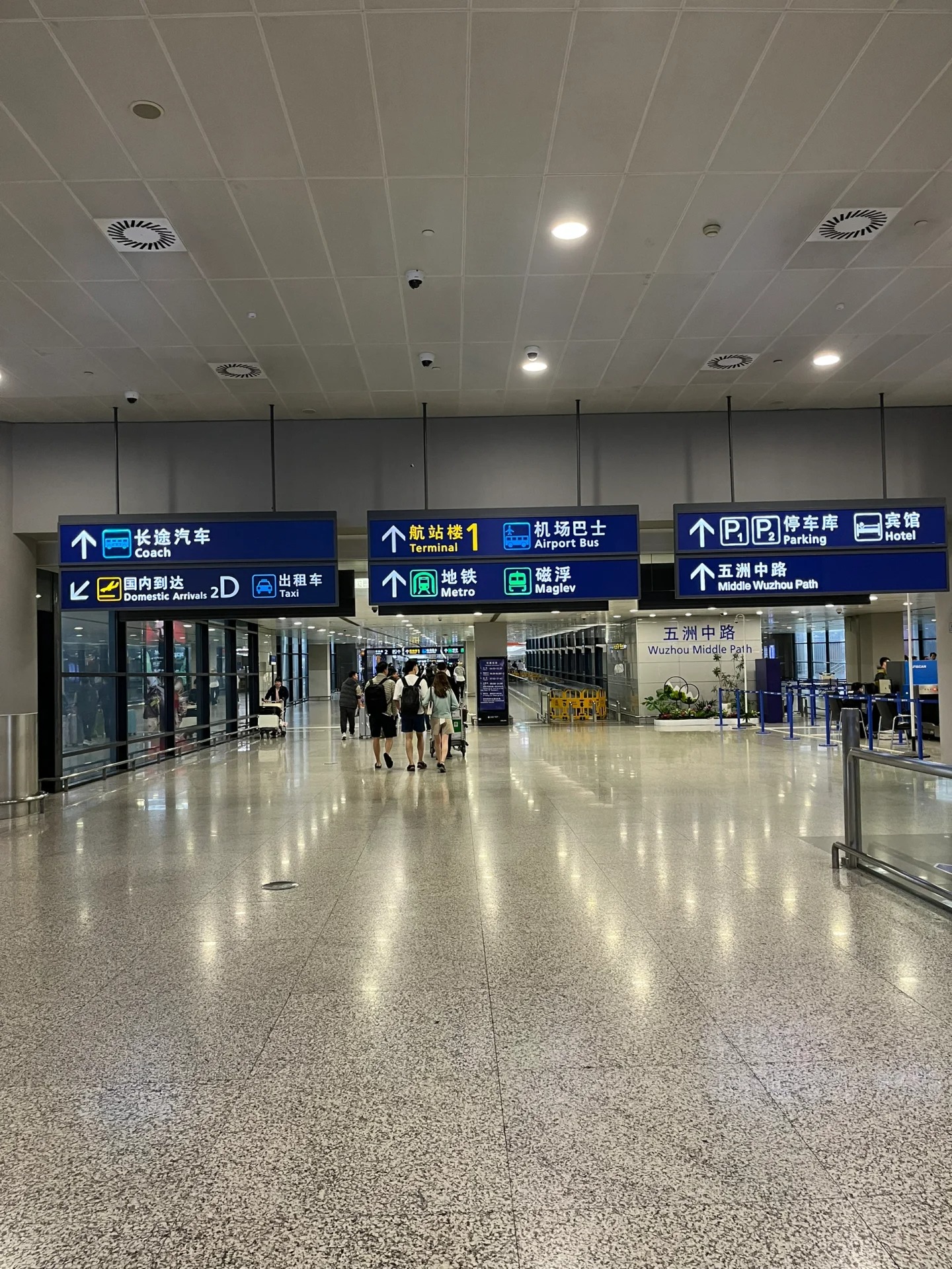 Overhead signs in the PVG T2 arrivals hall pointing to coach, taxi, Terminal 1, airport bus, metro, maglev, parking and hotels