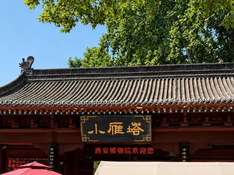The tiled gate roof at the entrance, with a black-and-gold plaque reading 小雁塔 and a red LED strip beneath it reading 西安博物院欢迎您.