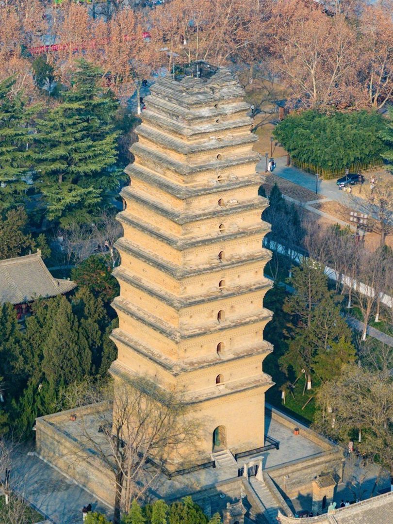 An elevated view down onto the Small Wild Goose Pagoda, its crown ending in a flat rough stump fitted with a modern guardrail rather than a spire, surrounded by evergreens and temple roofs.