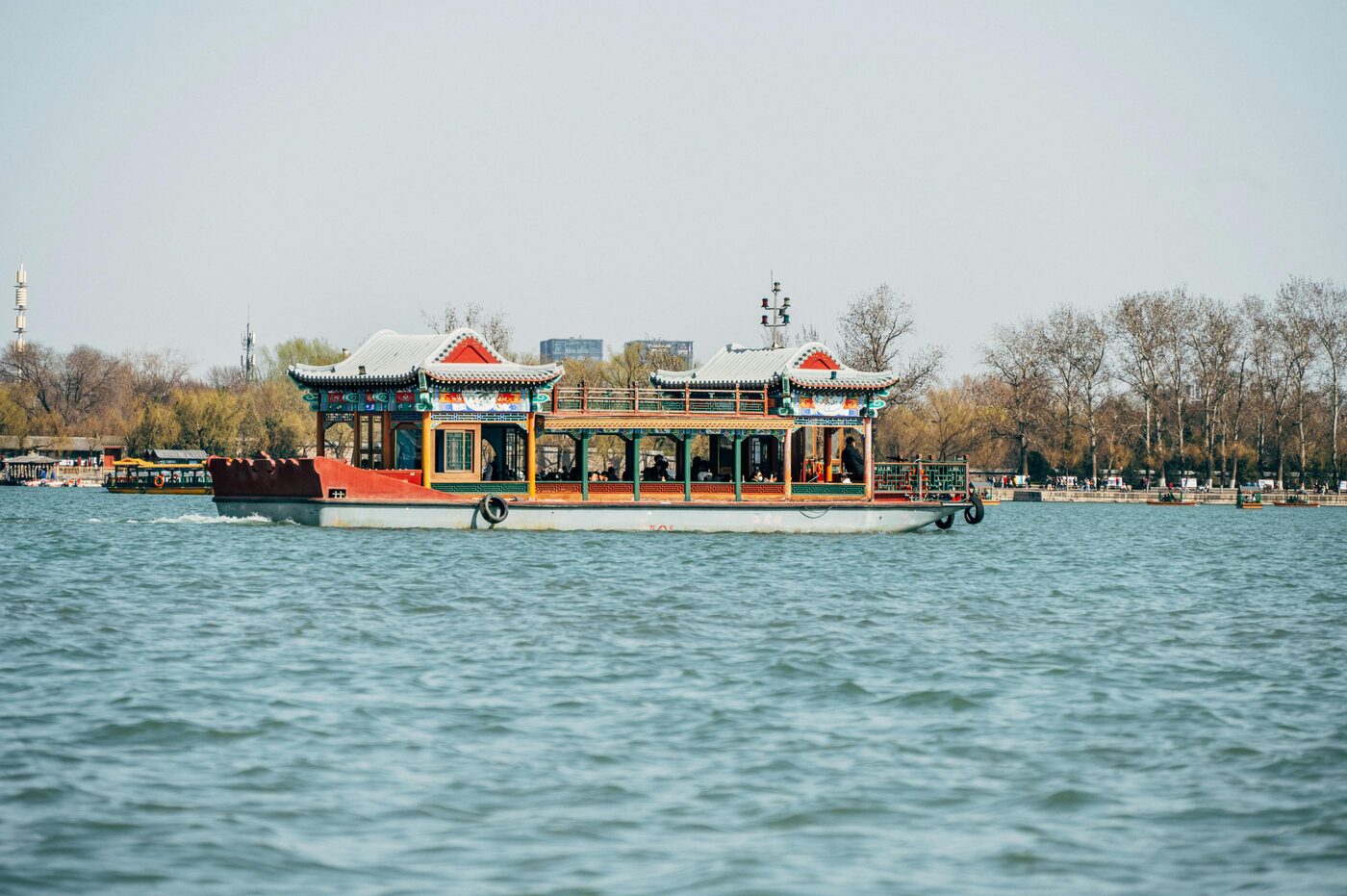 A traditional pavilion-style tour boat on Kunming Lake at the Summer Palace, Beijing, with willow-lined shores behind.