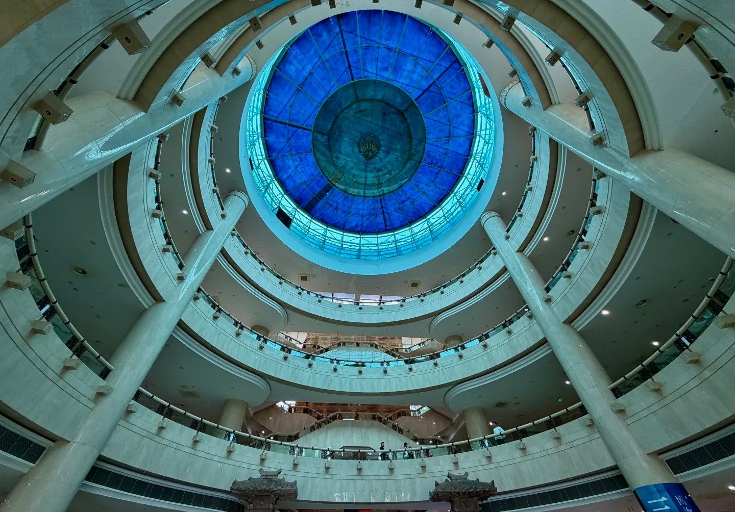 Looking up through the museum's circular atrium at a deep-blue glass dome, ringed by four tiers of curved balconies.