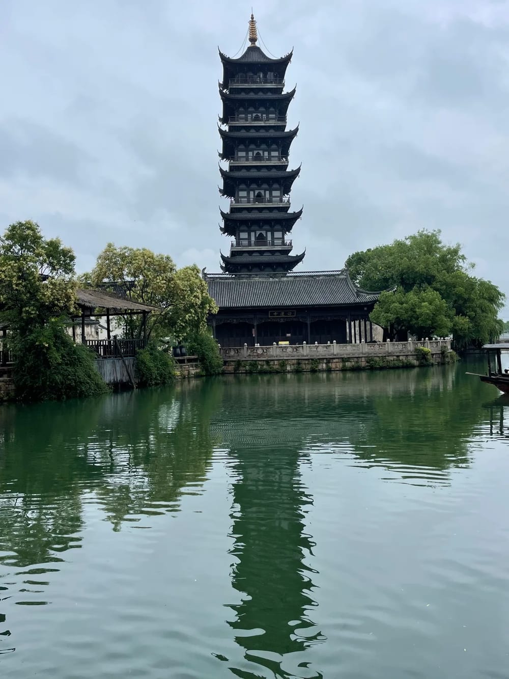 The seven-storey White Lotus Pagoda and the hall of Bailian Temple in Wuzhen, reflected full-length in the still green canal in front of them.