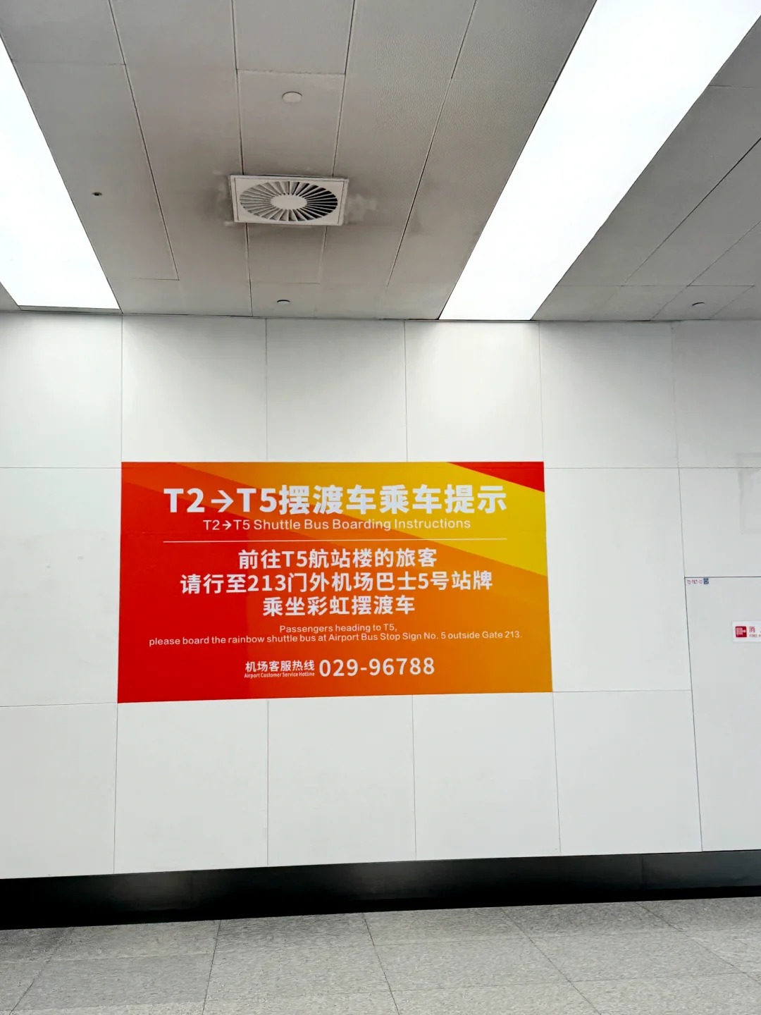 Bilingual wall notice in Terminal 2 directing passengers for Terminal 5 to airport bus stop sign number 5 outside gate 213