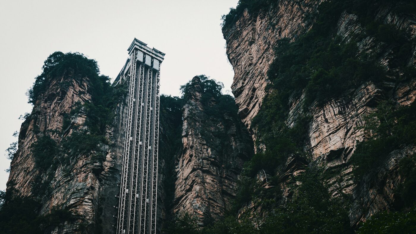 The Bailong Elevator — a glass lift bolted to a sandstone cliff inside Zhangjiajie National Forest Park, carrying visitors up to the Yuanjiajie plateau.