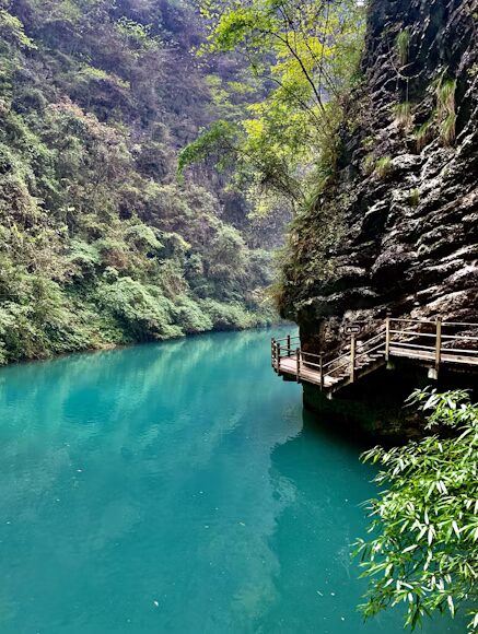A clear emerald pool and cliffside boardwalk along the Golden Whip Stream valley on the floor of Zhangjiajie National Forest Park.